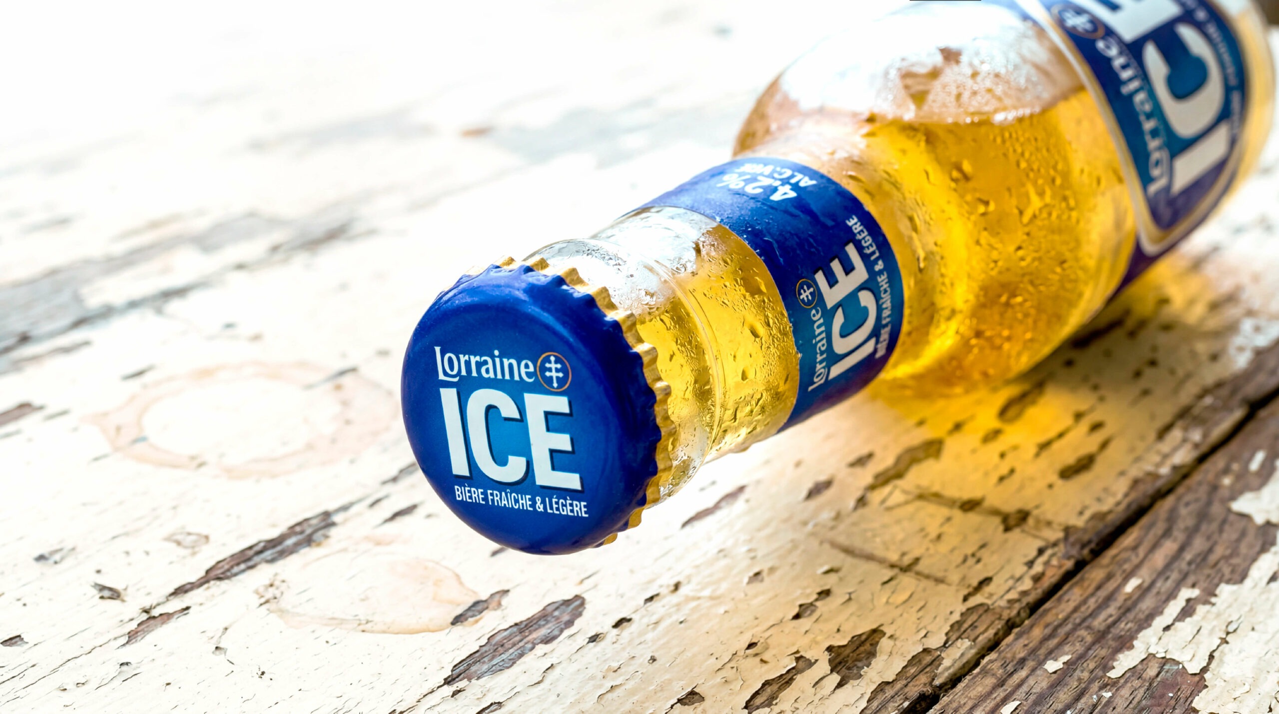 Bière Lorraine Ice posée à plat sur une table en bois, vue rapprochée sur la capsule